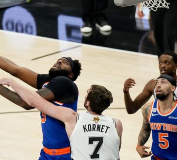 San Antonio Spurs center Luke Kornet reaches across New York Knicks center Mitchell Robinson as he goes up with the ball.