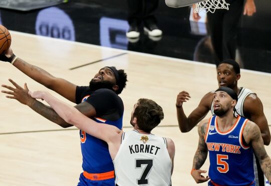 San Antonio Spurs center Luke Kornet reaches across New York Knicks center Mitchell Robinson as he goes up with the ball.
