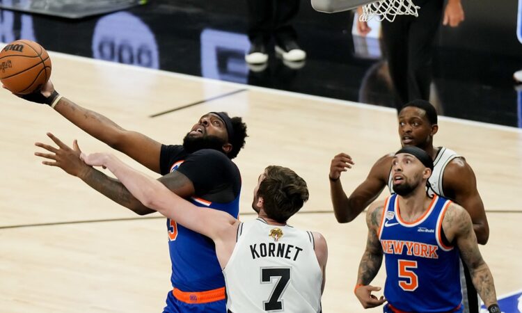 San Antonio Spurs center Luke Kornet reaches across New York Knicks center Mitchell Robinson as he goes up with the ball.