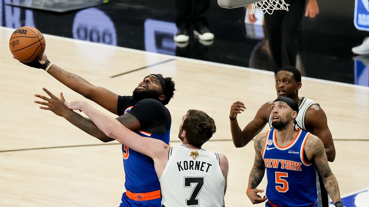 San Antonio Spurs center Luke Kornet reaches across New York Knicks center Mitchell Robinson as he goes up with the ball.