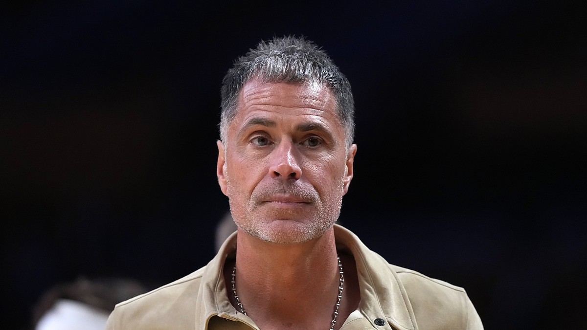 Los Angeles Lakers general manager Rob Pelinka, wearing a tan suede shirt jacket, looks on from courtside.