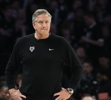 Minnesota Timberwolves head coach Chris Finch stands on the sideline with his hands on his hips during a playoff game.