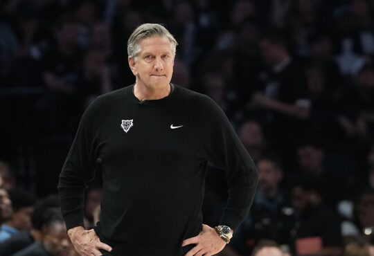 Minnesota Timberwolves head coach Chris Finch stands on the sideline with his hands on his hips during a playoff game.