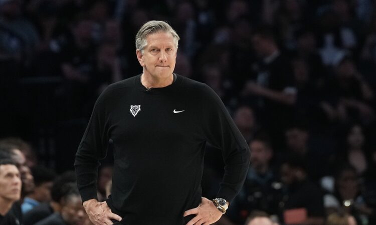 Minnesota Timberwolves head coach Chris Finch stands on the sideline with his hands on his hips during a playoff game.