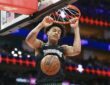 Minnesota Timberwolves forward Joan Beringer hangs on the rim with both hands as the ball drops through the net.