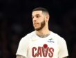 Cleveland Cavaliers guard Lonzo Ball looks toward the court in a white Cavs jersey.