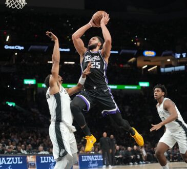 Sacramento Kings guard Ben Simmons rises for a shot between two San Antonio Spurs defenders near the basket.