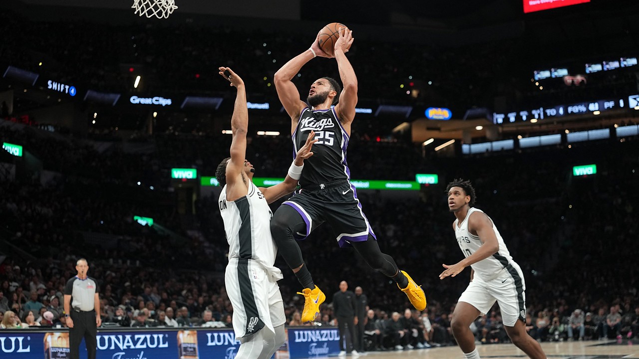 Sacramento Kings guard Ben Simmons rises for a shot between two San Antonio Spurs defenders near the basket.